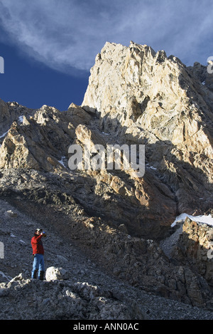 Man sitting on boulder drinking from water bottle below the Grand Teton Lower Saddle Grand Teton National Park Stock Photo