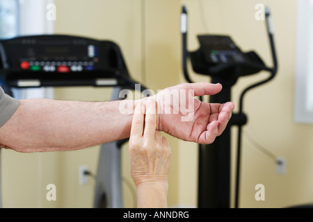 Woman checking pulse rate of man in the gym. Stock Photo