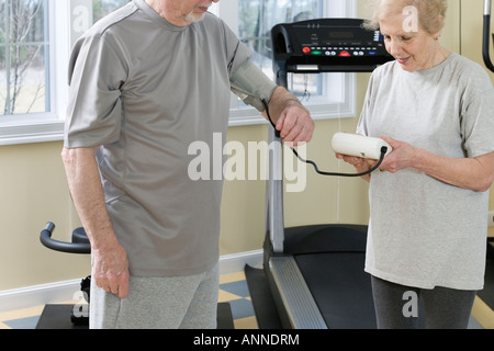 Wife checking blood pressure of husband in the gym. Stock Photo