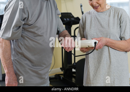 Wife checking blood pressure of husband in the gym. Stock Photo