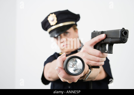 Police woman pointing handgun and holding flashlight. Stock Photo