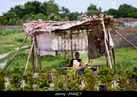 Young Gambian sitting in the shade of an empty stall by the roadside in the Gambia, west Africa Stock Photo