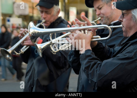 Horizontal close up of three men playing trumpets in a marching jazz band outside in Oxford Street Stock Photo