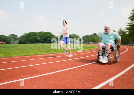 Young man racing with a handicapped senior man on a racetrack. Stock Photo