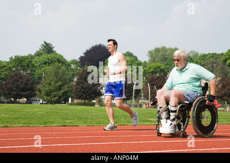 Young man racing with a handicapped senior man on the racetrack. Stock Photo