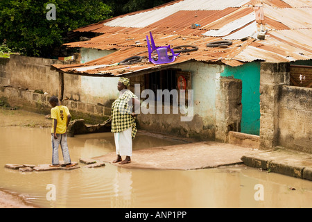 Gambian mother and son outside their village hut during the wet rainy season in the Gambia, west Africa Stock Photo