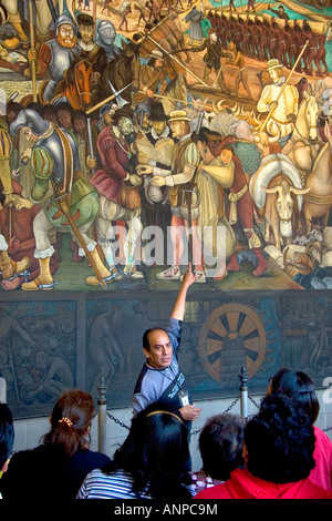 A tour guide showing tourists a mural painted by Diego Rivera at the National Palace in Mexico City Mexico Stock Photo