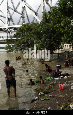 People bathe and wash in the Hooghly River, near the Howrah Bridge, in Kolkata, India. Stock Photo