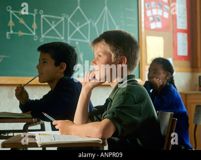 Boy (11-12) at desk,resting on elbow, geometry diagrams on wall behind Stock Photo
