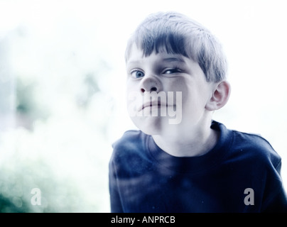 Small boy pressing his nose and cheek against some glass Stock Photo