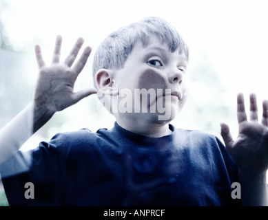 Small boy pressing his cheek against some glass Stock Photo
