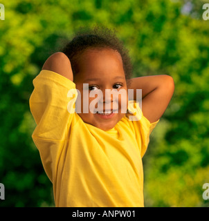 Infant African Caribbean black 2-4 years happy attractive girl poses for camera in sunny garden Stock Photo