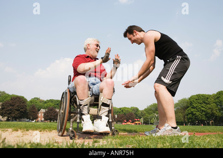 Young man gesturing with a handicapped senior man. Stock Photo