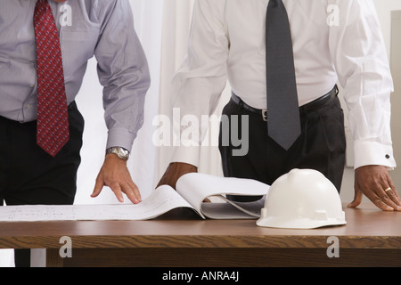 Mid section view of two engineers looking at a blueprint in an office Stock Photo