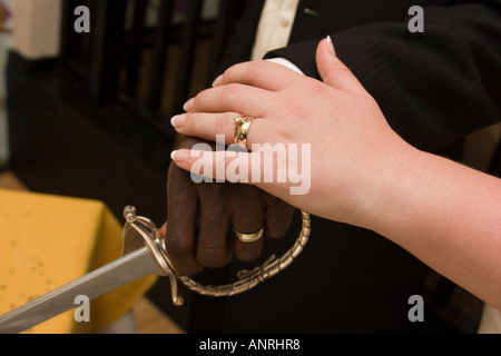 weddings hands and rings of bride and groom in mixed race marriage cutting wedding cake Stock Photo