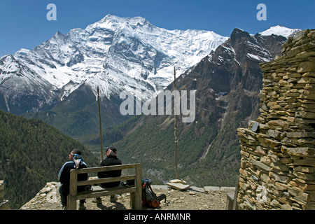 Trekkers resting at Ghyaru village. On the background the Annapurna II (7937 m). Annapurna circuit trek. Nepal Stock Photo