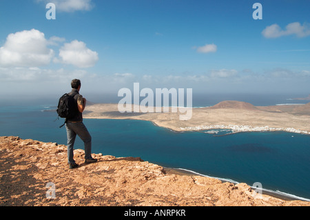 Hiker looking towards La Graciosa island from El mirador del Rio on neighbouring Lanzarote. Stock Photo