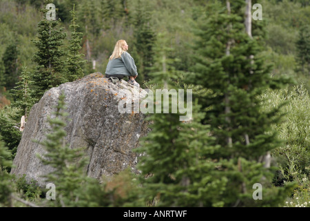 A hiker on a rock in Glacier National Park on the shore of Gunsight Lake Stock Photo