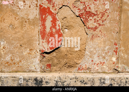 a close up abstract view of cracked masonry on an old wall Brick red paint has peeled away from the damaged surface Stock Photo