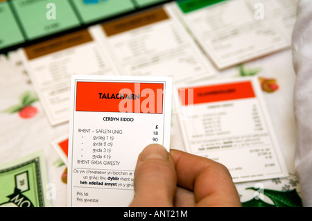 person playing welsh language Monopoly board game cymraeg wales - close up of hand holding TALACHARN property card (cerdyn eiddo Stock Photo