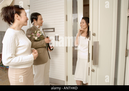 Mature woman greeting mature couple at front door Stock Photo