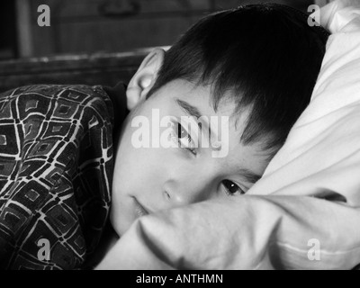 Close up portrait of young boy dreaming on the bed. Black and white Stock Photo