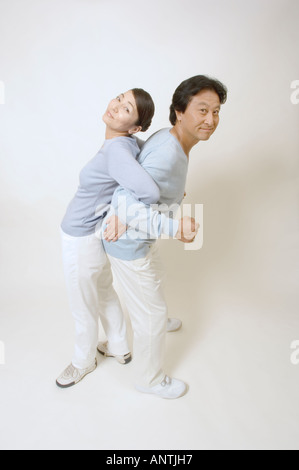Mature couple standing back to back, arms locked Stock Photo
