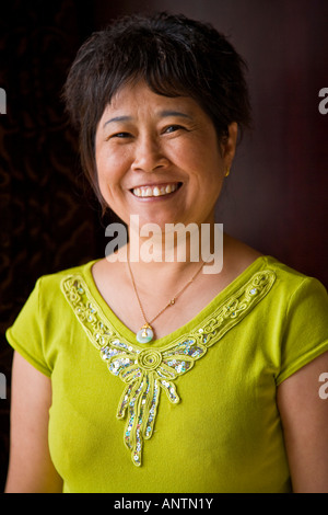 Middle aged asian oriental Chinese woman in yellow dress smiling looking to camera Beijing China JMH2956 Stock Photo