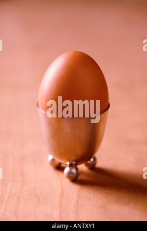 Boiled egg in silver eggcup on wooden table Stock Photo