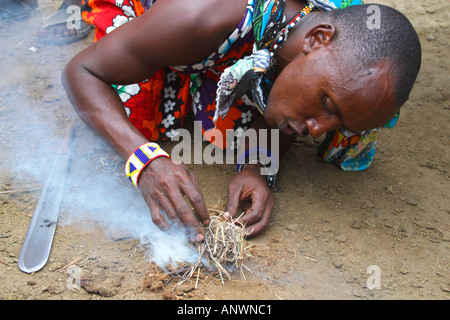 Maasai warrior making fire in village in Masai Mara National Nature Reserve Kenya East Africa Stock Photo