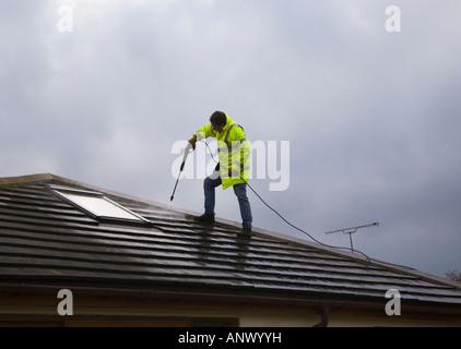 Man cleaning the roof of a house using a high pressure water jetwash jet spray. House exterior. UK Stock Photo