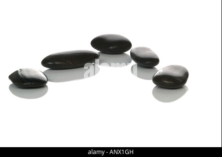 Five black pebbles with reflections on a white background Stock Photo