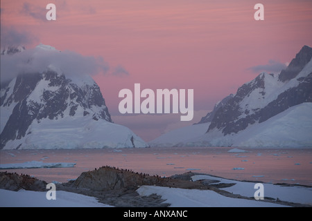 The sky is lit a brilliant pink by alpenglow at sunset over the Lemaire Channel and surrounding mountains and glaciers Stock Photo