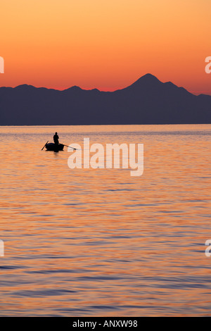 silhouet of a lone fisherman standing in a rowing boat fishing Stock Photo