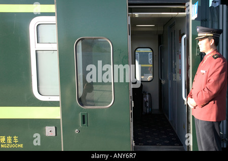 Steward welcomes passengers on board the Tangula Express / Sky Train, from Golmud, Qinghai province, China, to Lhasa, Tibet Stock Photo