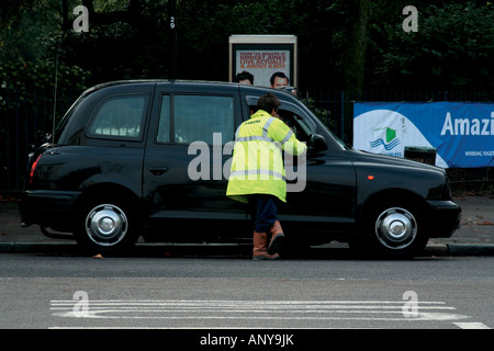 Man in luninescent coat talking to a London Cab Driver Stock Photo