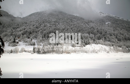 Lac de Montriond, partly frozen over in winter, with snow all around,  Alps, France Stock Photo