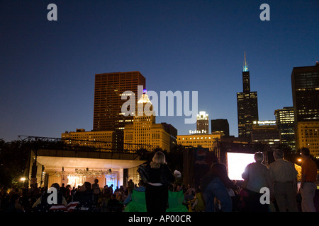 ILLINOIS Chicago Crowd of people sitting in Grant Park Petrillo outdoor stage for Jazz Festival city skyline at dusk Stock Photo