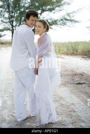 Bride and groom walking on sand Stock Photo