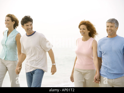 Two mature couples walking on beach Stock Photo
