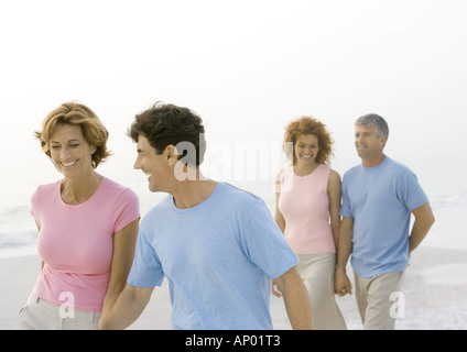 Two mature couples walking on beach Stock Photo