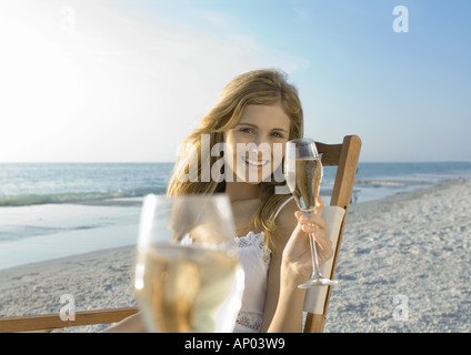 Young woman drinking champagne on beach Stock Photo