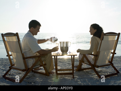 Newlyweds, husband serving wife champagne on beach Stock Photo