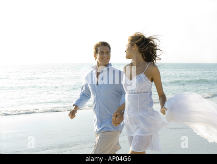 Couple walking on beach, smiling at each other Stock Photo