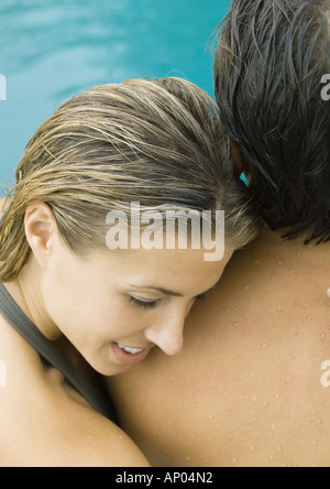 Couple near swimming pool, woman resting head on man's shoulder Stock Photo