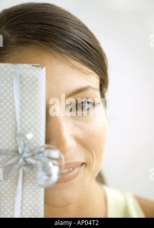 Woman holding gift in front of face Stock Photo