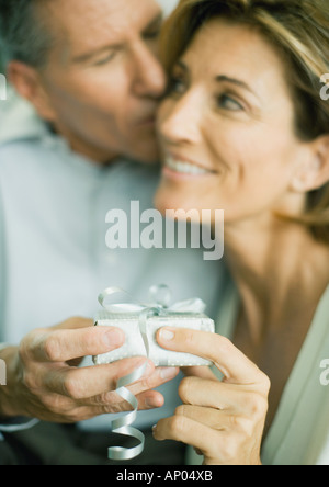 Mature couple with present, man kissing woman's cheek Stock Photo