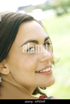 Young woman, looking over shoulder, smiling at camera
