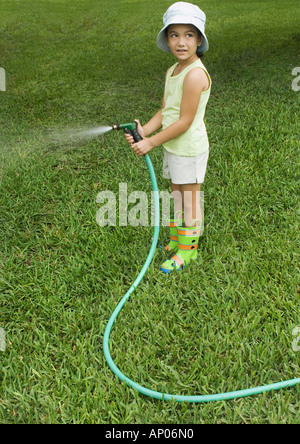 Little girl standing with garden hose Stock Photo