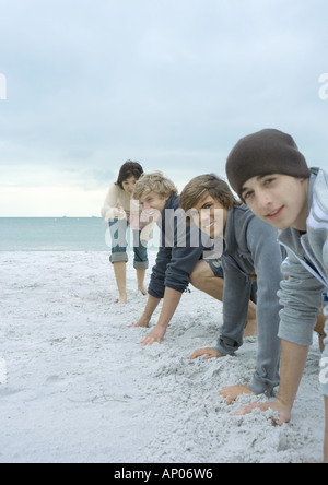 Young adult friends about to race on beach Stock Photo